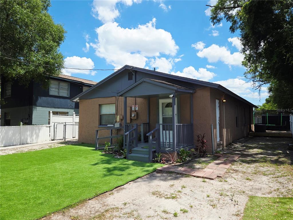 A single-story house with a brown stucco exterior, a gray front porch, and artificial turf — 1617 E IDELL STREET, TAMPA, FL