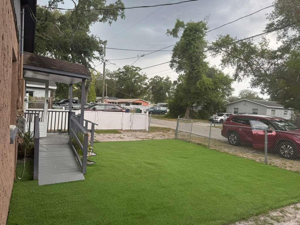 A small house exterior features a wooden wheelchair ramp leading to a covered porch entrance — 1617 E IDELL STREET, TAMPA, FL