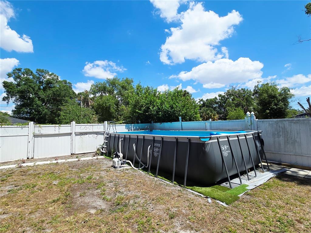 An above-ground rectangular swimming pool sits in a backyard enclosed by a white vinyl fence — 1617 E IDELL STREET, TAMPA, FL