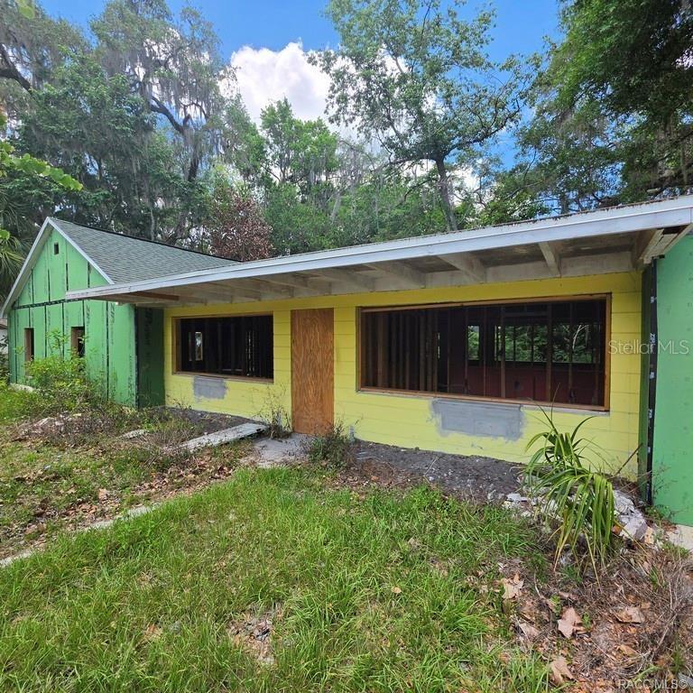 An exterior view of a house under renovation with green sheathing and yellow block walls — 8869 E OGDEN LANE, FLORAL CITY, FL