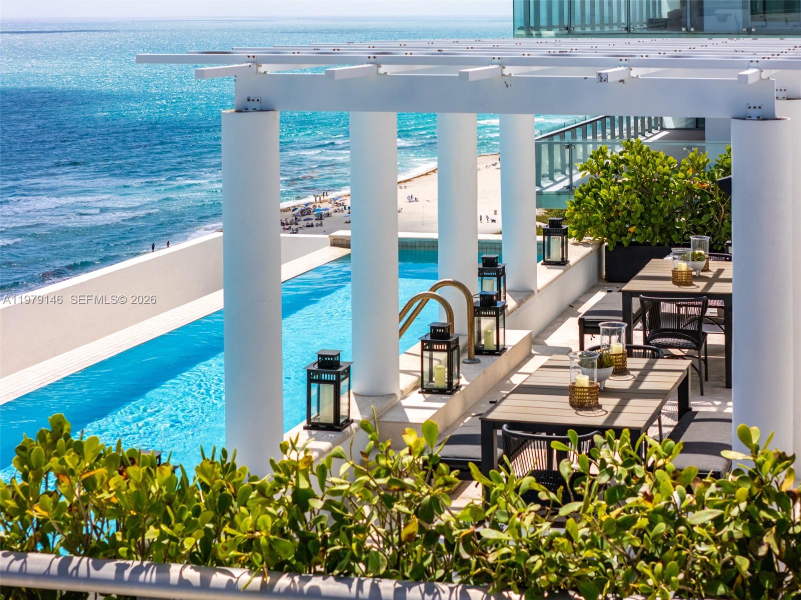 An outdoor terrace features a swimming pool, dining tables, and white columns overlooking the ocean — 5801 Collins Ave, Miami Beach FL 33140, MIAMI BEACH, FL