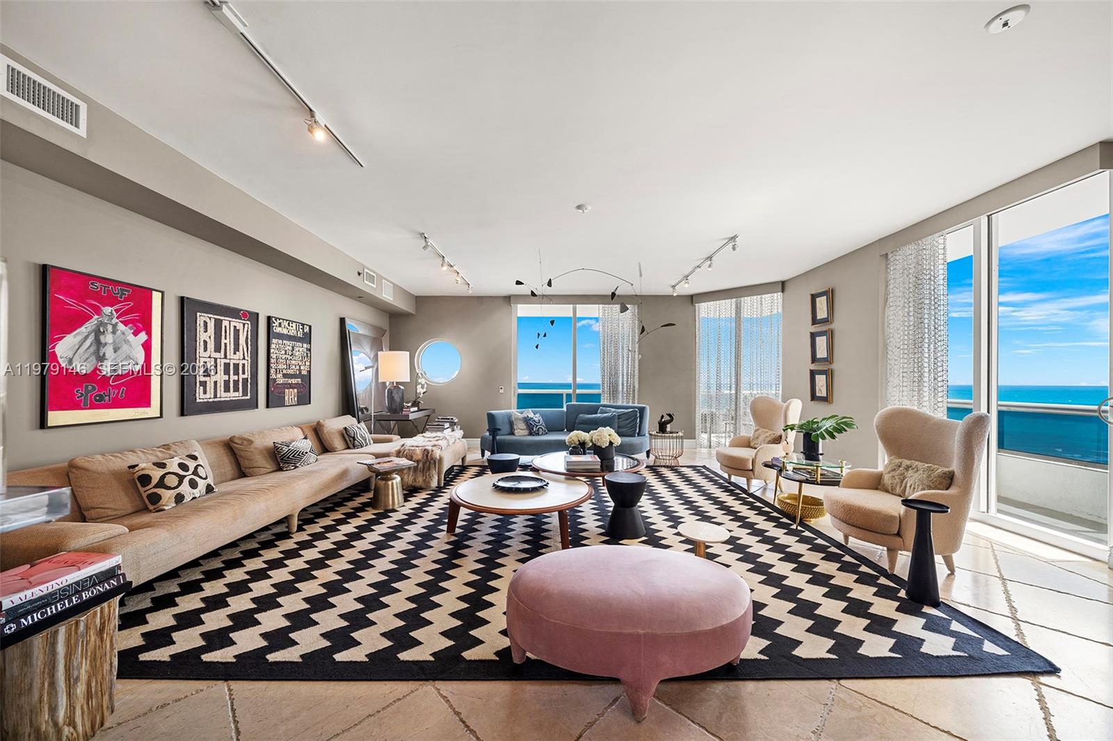 A spacious living room features a large chevron rug, modern furniture, and floor-to-ceiling ocean views — 5801 Collins Ave, Miami Beach FL 33140, MIAMI BEACH, FL