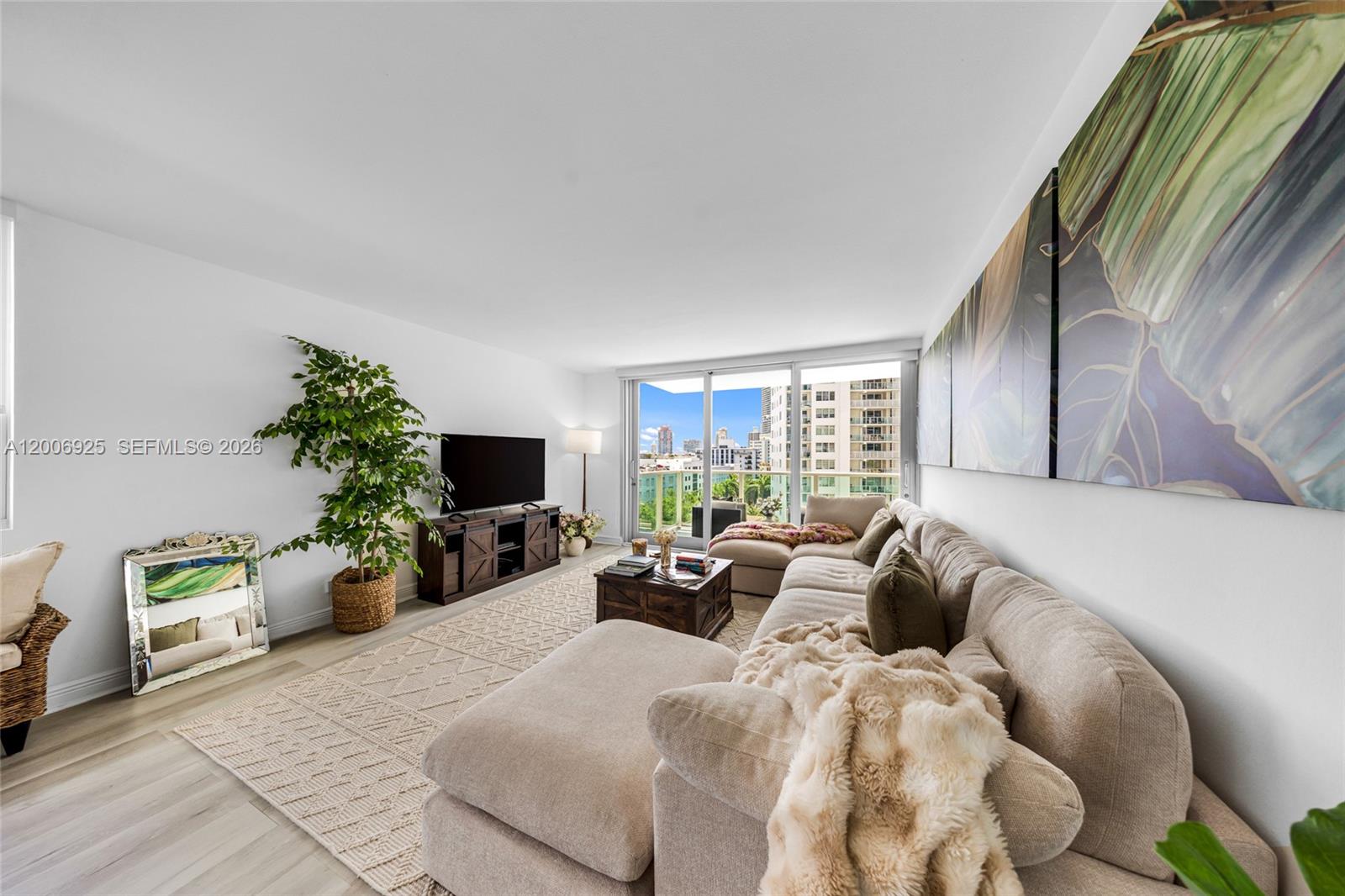 A living room features a large sectional sofa, a television console, and a balcony view — 1000 West Ave # 702, Miami Beach FL 33139, MIAMI BEACH, FL