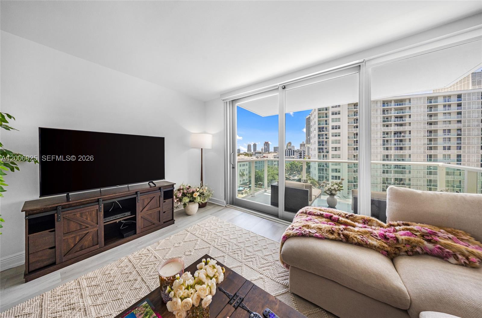 A living room features a television on a wooden console, a sofa, and a balcony — 1000 West Ave # 702, Miami Beach FL 33139, MIAMI BEACH, FL