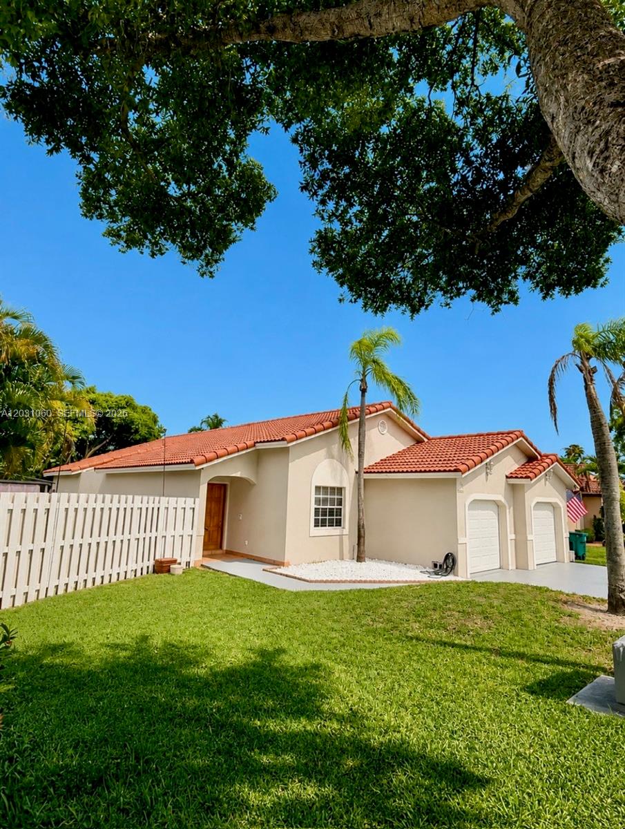 A single-story house with a red tile roof, beige stucco walls, and a white fence — 18145 NW 61st Ave, Hialeah FL 33015, HIALEAH, FL