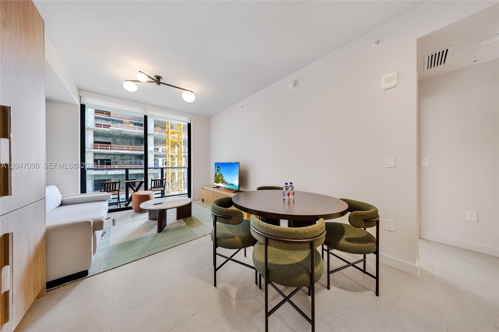 A modern living and dining area features a round table, green chairs, and balcony views — 11 NE 6th St # 2903, Miami FL 33132, MIAMI, FL