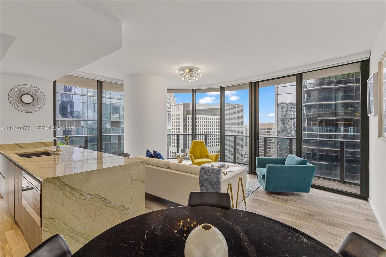 A modern living and dining area features floor-to-ceiling windows, marble countertops, and colorful furniture — 801 S Miami Ave # 4205, Miami FL 33130, MIAMI, FL
