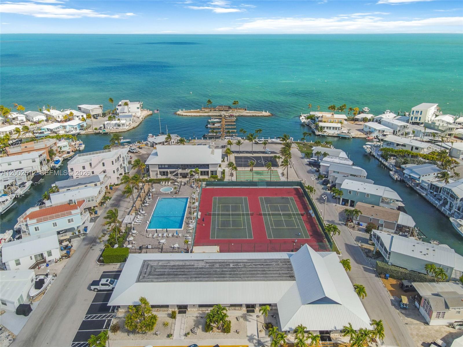 An aerial view shows a coastal community with tennis courts, a pool, and boat docks — 65821 OVERSEAS HIGHWAY Unit 110, Long Key FL 33001, LONG KEY, FL