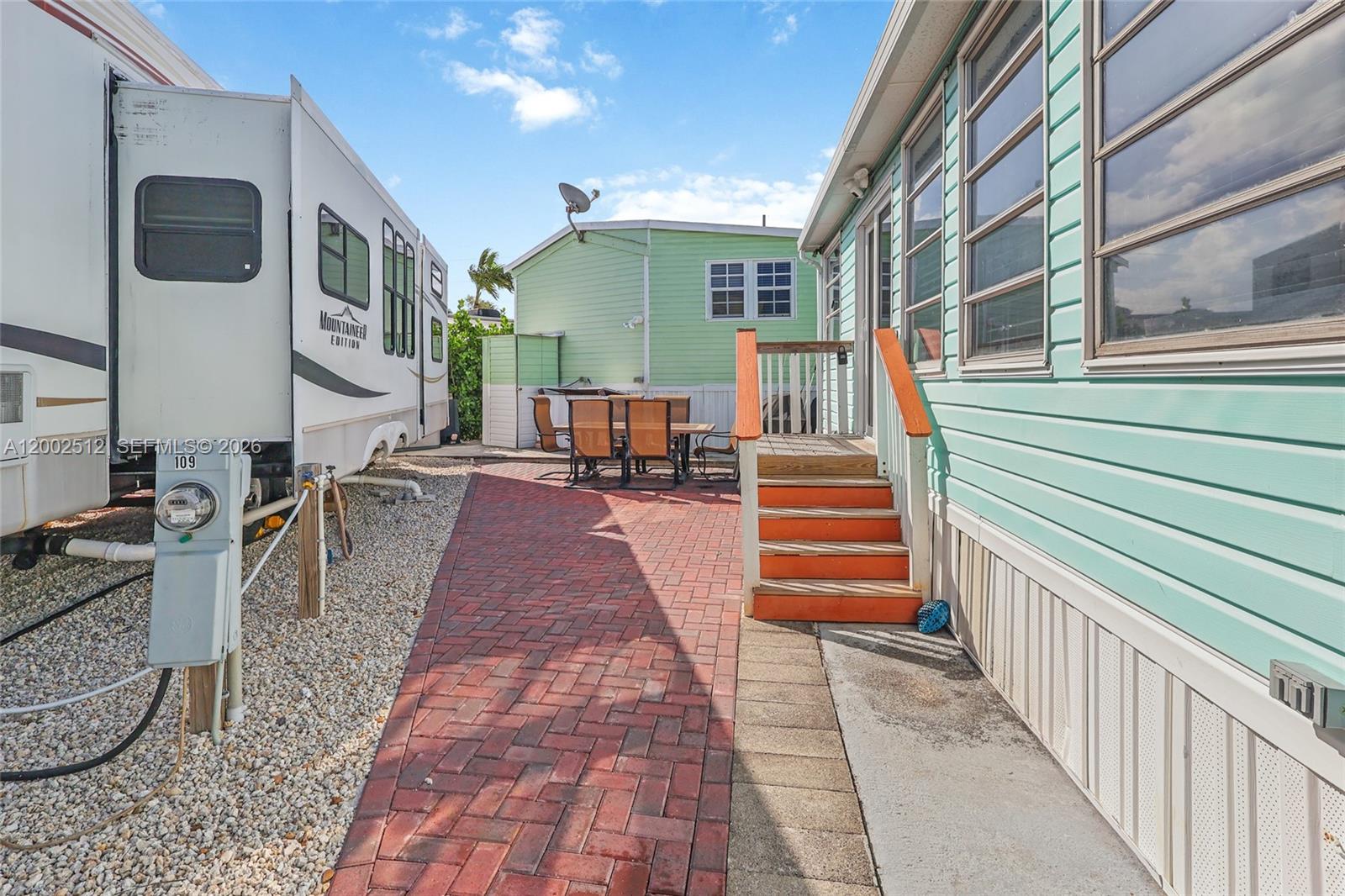 A brick patio sits between a parked RV and a light green mobile home — 65821 OVERSEAS HIGHWAY Unit 110, Long Key FL 33001, LONG KEY, FL