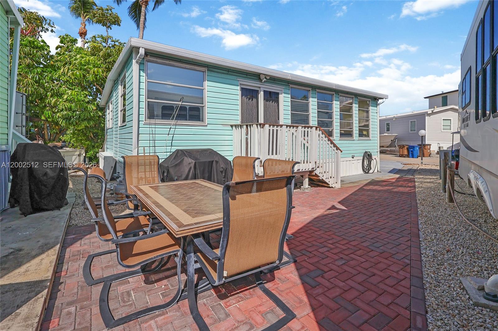 A light blue mobile home features a brick patio with a dining set outside — 65821 OVERSEAS HIGHWAY Unit 110, Long Key FL 33001, LONG KEY, FL
