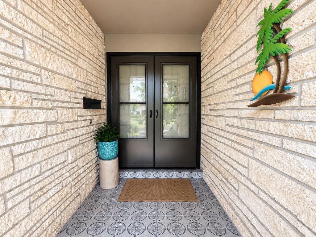 A covered entryway features stone walls, a patterned tile floor, and double glass doors — 8408 BOULDER PLACE, TAMPA, FL