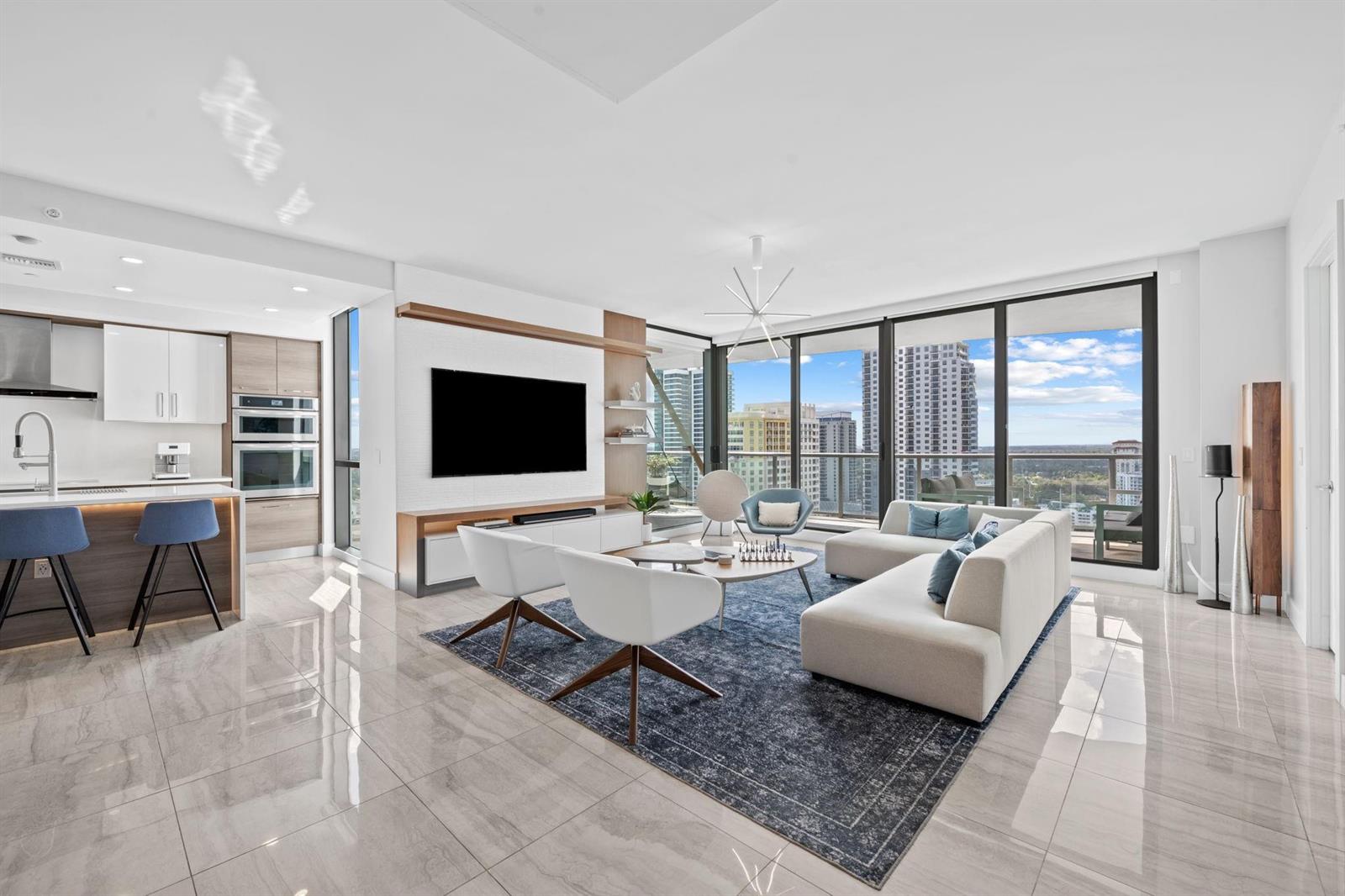 A modern open-concept living room and kitchen with floor-to-ceiling windows and city views — 100 E Las Olas Boulevard # 2404, Fort Lauderdale FL 33301, FORT LAUDERDALE, FL