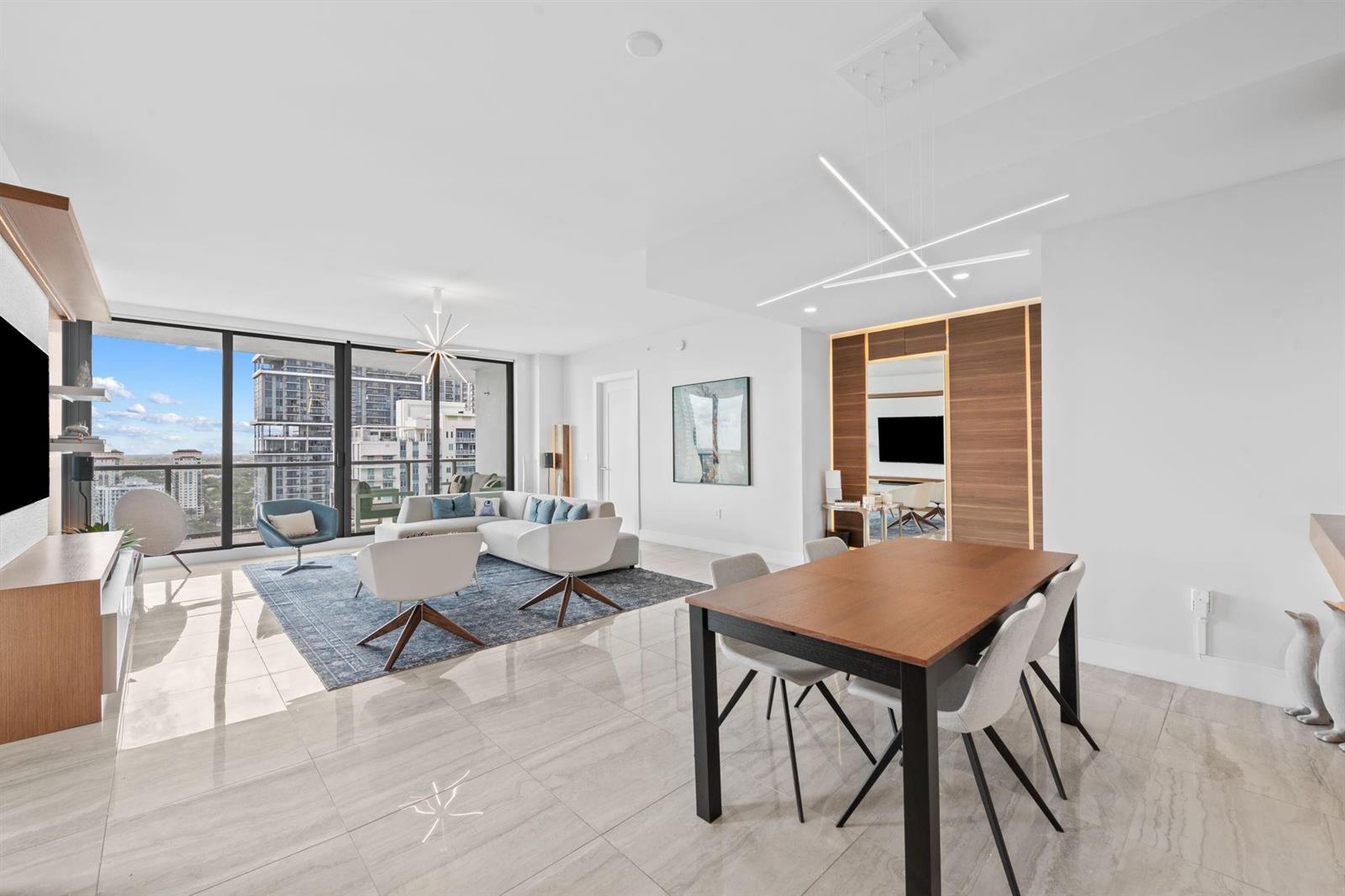 A modern open-concept living and dining area features tile floors, floor-to-ceiling windows, and city views — 100 E Las Olas Boulevard # 2404, Fort Lauderdale FL 33301, FORT LAUDERDALE, FL
