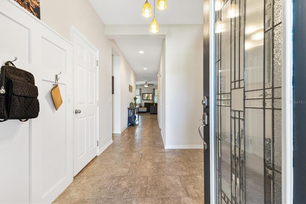 A tiled entryway leads down a hallway toward a living area with hanging pendant lights — 4110 ARLINGTON RIDGE BOULEVARD, LEESBURG, FL