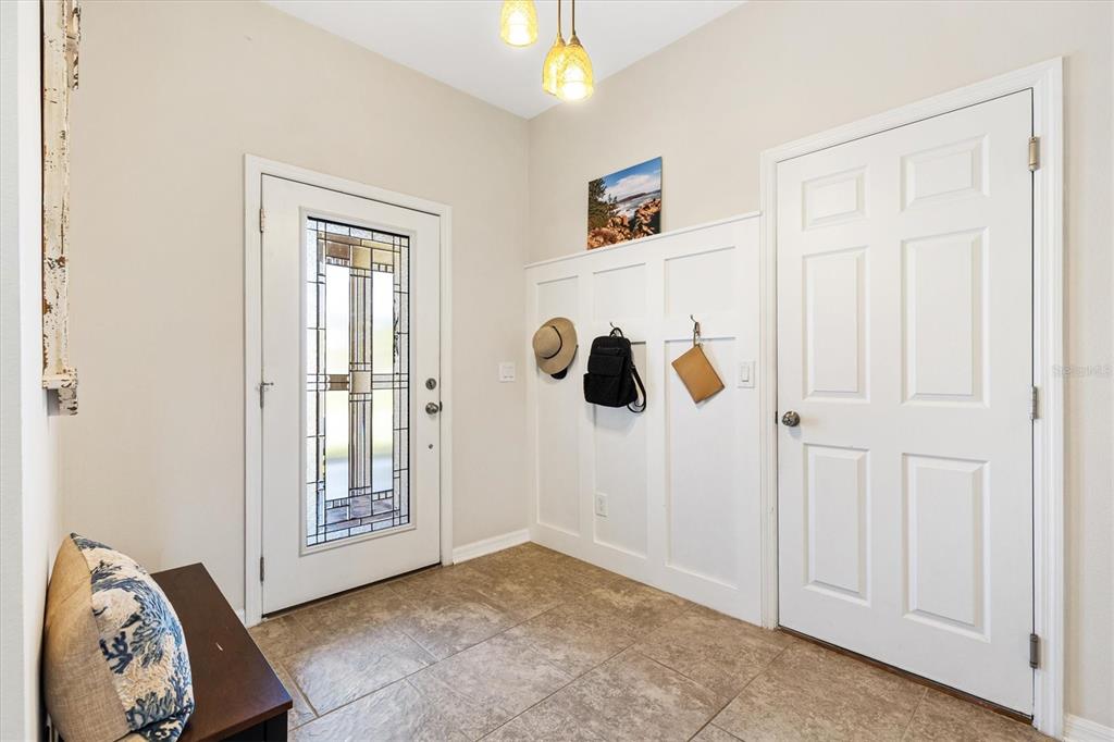 An entryway features tile flooring, white wainscoting with coat hooks, and two white doors — 4110 ARLINGTON RIDGE BOULEVARD, LEESBURG, FL