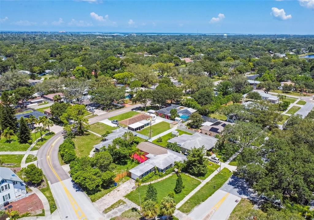 An aerial view shows a suburban neighborhood with houses, green lawns, and tree-lined streets — 210 BAKER AVENUE, CLEARWATER, FL