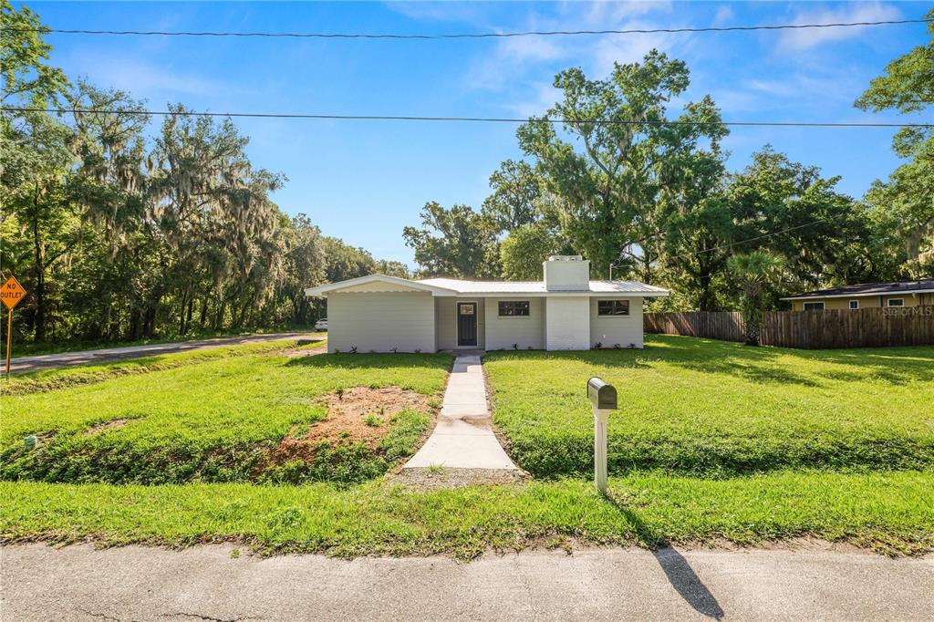 A single-story light gray house with a white chimney sits on a grassy lot — 1112 N PENNSYLVANIA AVENUE, PLANT CITY, FL