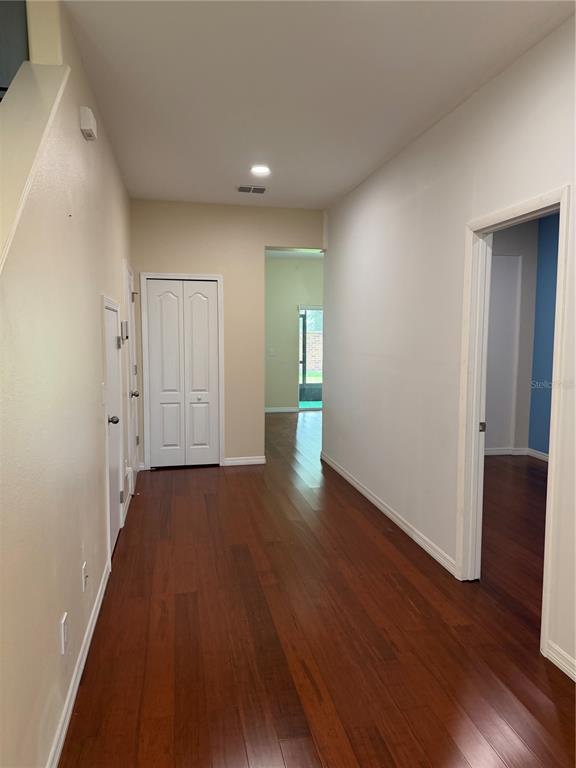 A hallway with hardwood floors leads to a doorway and a white closet door — 2914 RODRICK CIRCLE, ORLANDO, FL