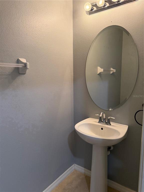 A small bathroom features a pedestal sink, an oval mirror, and a wall-mounted light fixture — 2914 RODRICK CIRCLE, ORLANDO, FL