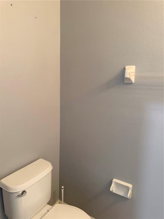 A bathroom corner features a white toilet, a wall-mounted toilet paper holder, and gray walls — 2914 RODRICK CIRCLE, ORLANDO, FL