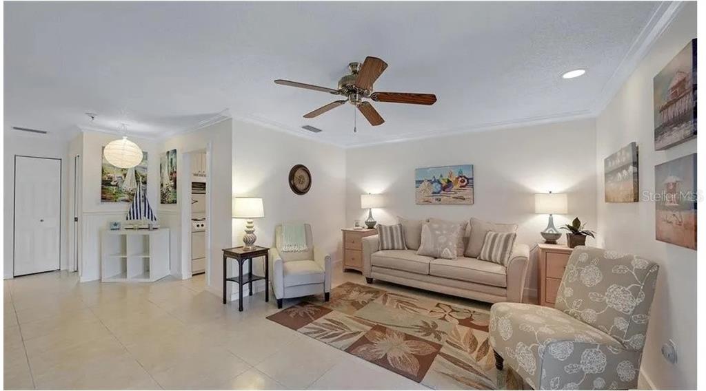 A living room features a beige sofa, two armchairs, a ceiling fan, and tile flooring — 2782 WOODGATE LANE UNIT 12, SARASOTA, FL