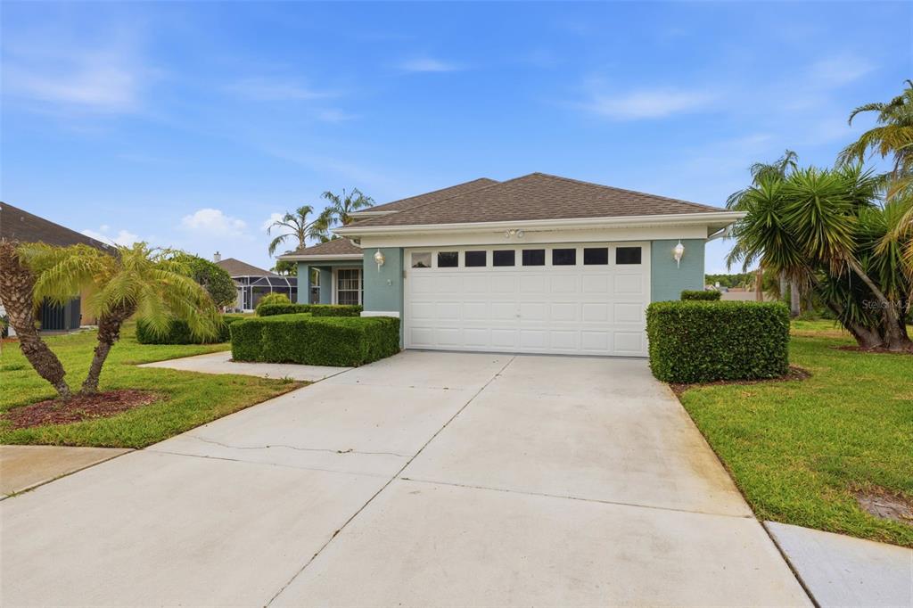 A single-story house with a two-car garage, light blue siding, and manicured hedges — 1125 DALESIDE LANE, NEW PORT RICHEY, FL