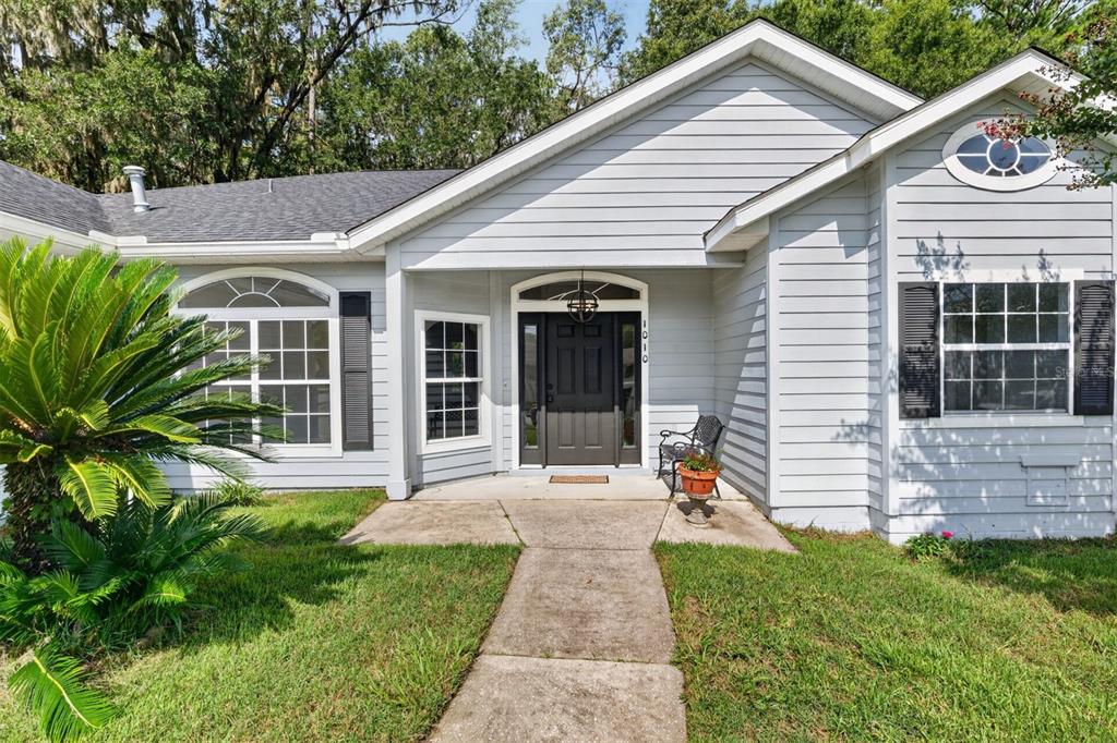 The exterior of a light gray single-story house with a dark front door and walkway — 1010 NW 120TH STREET, GAINESVILLE, FL