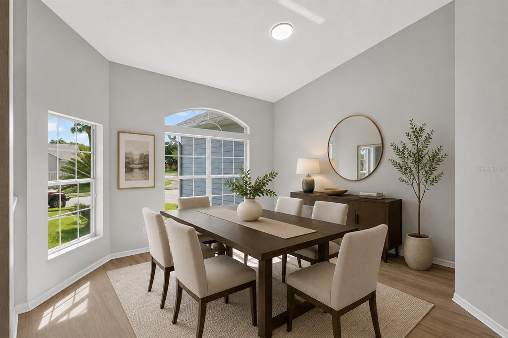 A dining room features a dark wood table, six upholstered chairs, and a round wall mirror — 1010 NW 120TH STREET, GAINESVILLE, FL