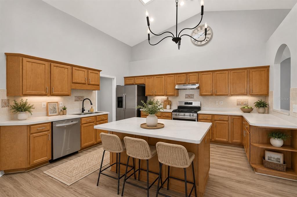 A kitchen with wood cabinets, white countertops, a central island, and a vaulted ceiling — 1010 NW 120TH STREET, GAINESVILLE, FL