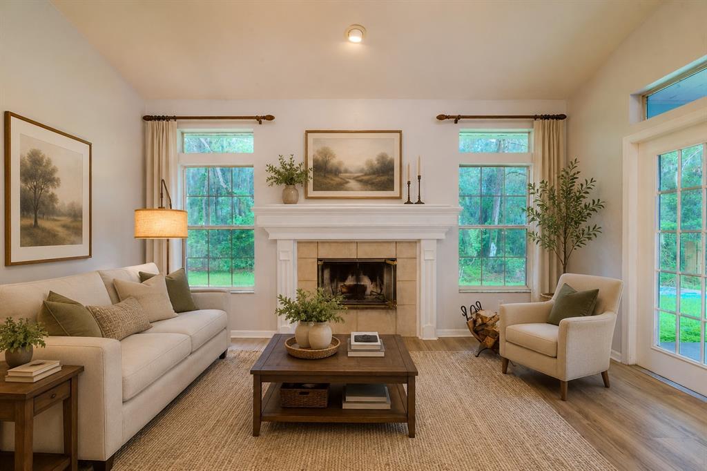 A living room features a fireplace, a beige sofa, an armchair, and large windows — 1010 NW 120TH STREET, GAINESVILLE, FL