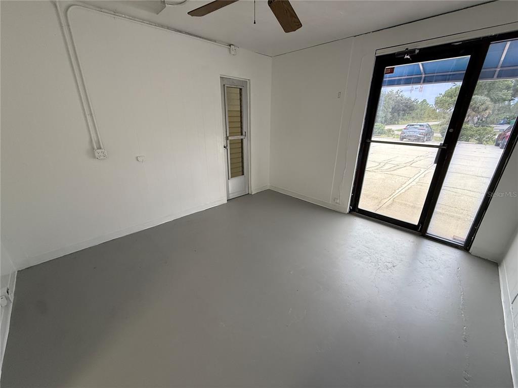 An empty room with gray painted floors, white walls, a ceiling fan, and glass doors — 517 PAUL MORRIS DRIVE UNIT B4, ENGLEWOOD, FL