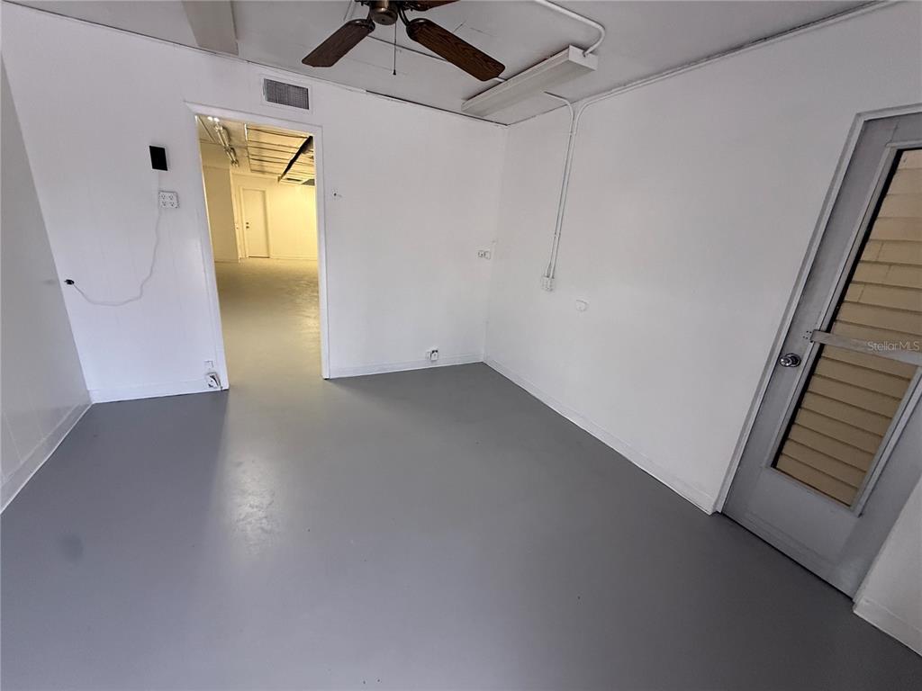 A room with gray flooring, white walls, a ceiling fan, and a doorway to another space — 517 PAUL MORRIS DRIVE UNIT B4, ENGLEWOOD, FL