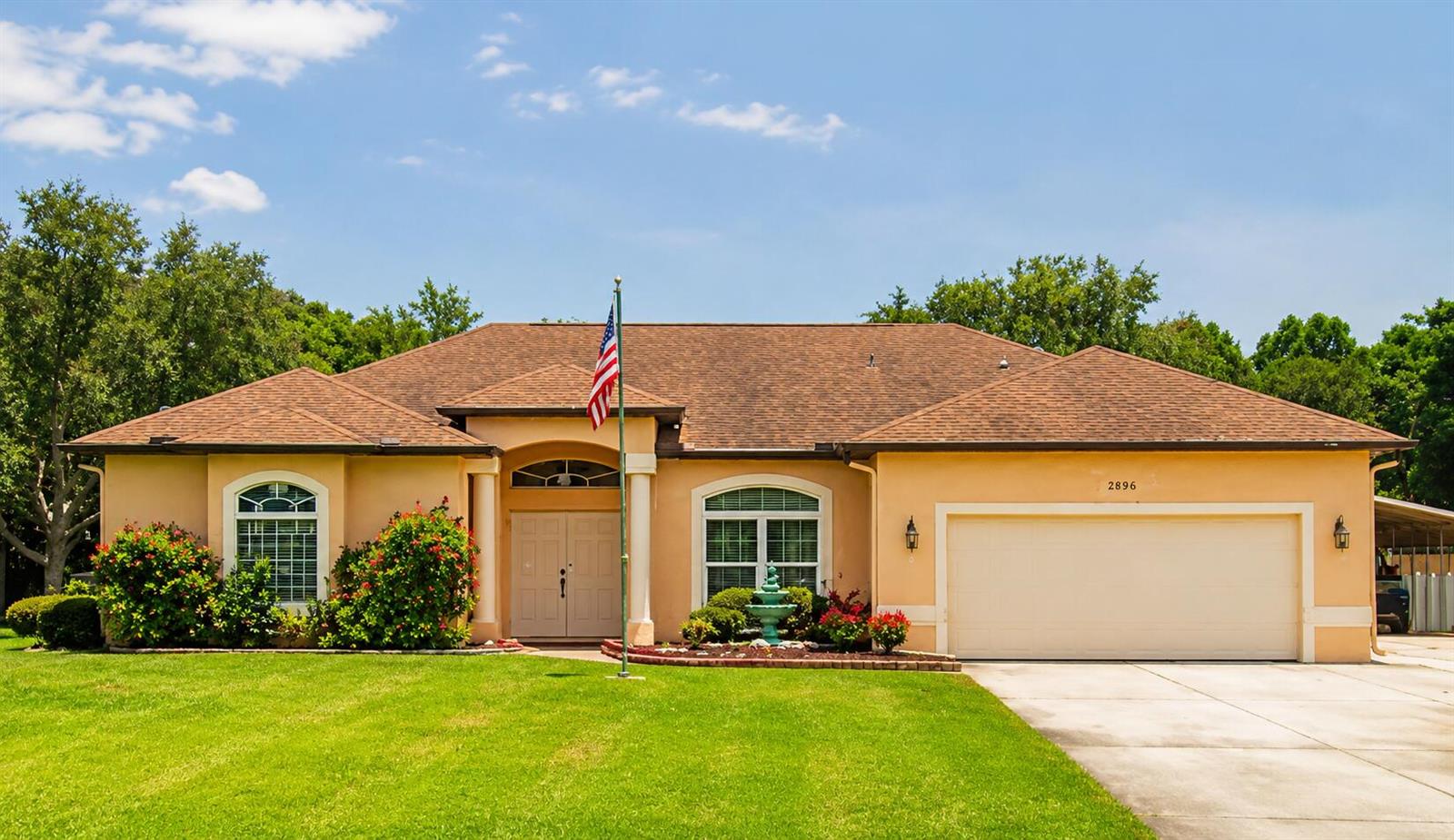 A single-story house with a tan stucco exterior, a two-car garage, and a front lawn — 5508 Silver Oak Drive, Fort Pierce FL 34982, FORT PIERCE, FL