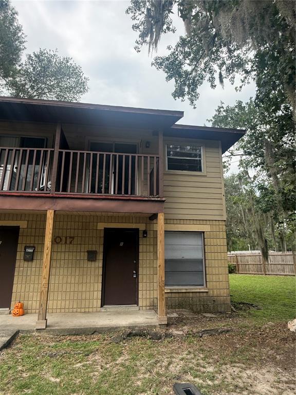 A two-story apartment building exterior features a ground-level entrance, a second-story balcony, and tan brick siding — 4017 SW 22ND ROAD UNIT B, GAINESVILLE, FL