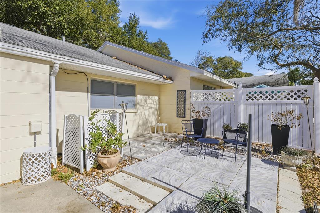 A patio with light-colored pavers, outdoor furniture, and a white lattice privacy fence — 8868 SW 97TH LANE ROAD UNIT G, OCALA, FL