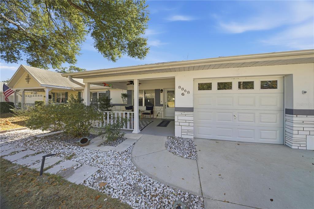 A single-story house features a white garage, a covered front porch, and a gravel yard — 8868 SW 97TH LANE ROAD UNIT G, OCALA, FL