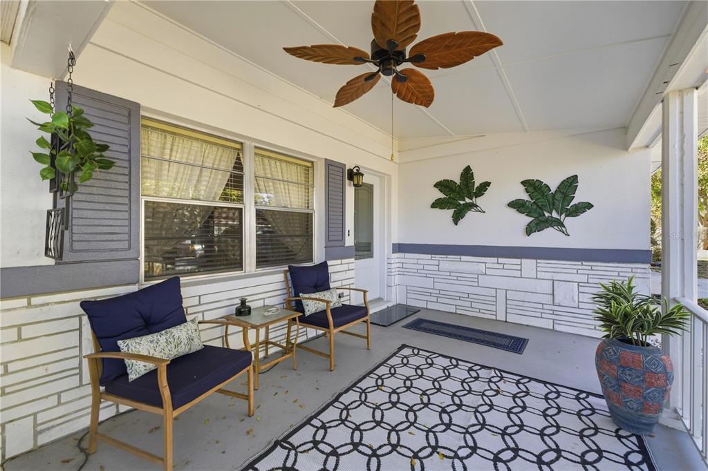 A covered front porch features two blue chairs, a patterned rug, and tropical-themed wall decor — 8868 SW 97TH LANE ROAD UNIT G, OCALA, FL