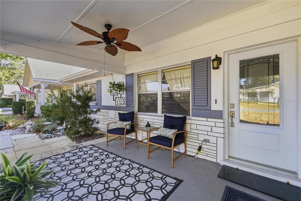 A covered front porch features a ceiling fan, two chairs, and a white front door — 8868 SW 97TH LANE ROAD UNIT G, OCALA, FL