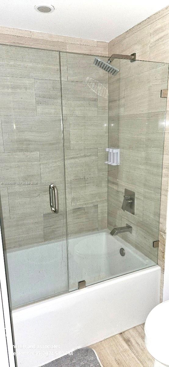 A bathroom features a bathtub with a glass shower door and light-colored tiled walls — 1300 Brickell Bay Dr # 2112, Miami FL 33131, MIAMI, FL