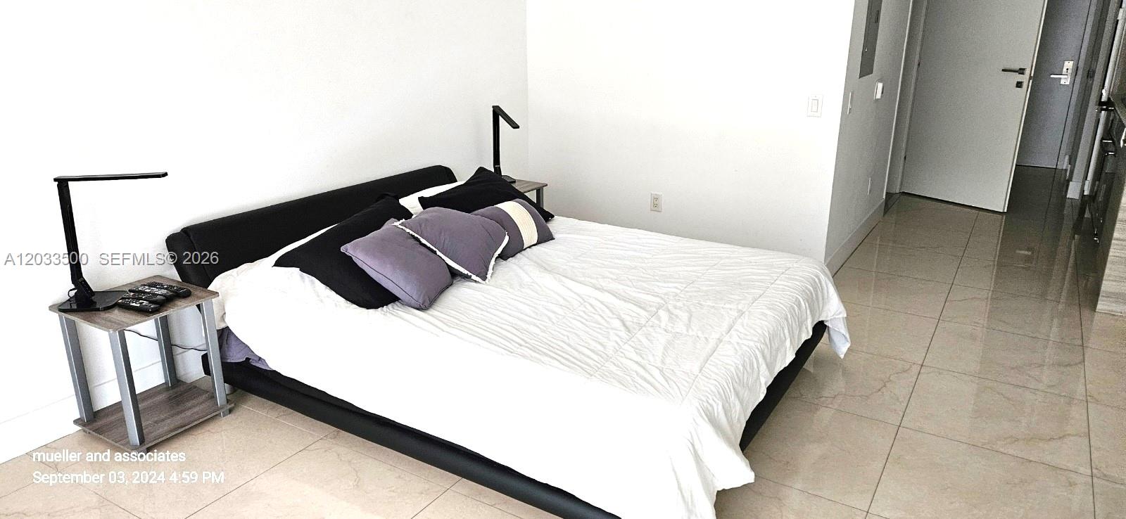 A bedroom features a black platform bed, white bedding, and light-colored tile flooring — 1300 Brickell Bay Dr # 2112, Miami FL 33131, MIAMI, FL
