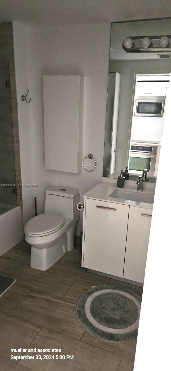 A bathroom features a white vanity, a toilet, a wall cabinet, and a large mirror — 1300 Brickell Bay Dr # 2112, Miami FL 33131, MIAMI, FL