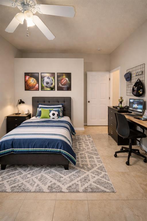 A bedroom features a twin bed, a desk, a ceiling fan, and sports-themed wall art — 6002 RENAISSANCE COURT, ST CLOUD, FL