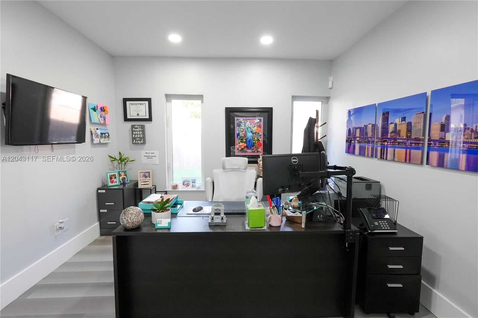 A home office features a dark desk, white chair, two windows, and wall-mounted artwork — 8125 SW 120th St, Pinecrest FL 33156, PINECREST, FL