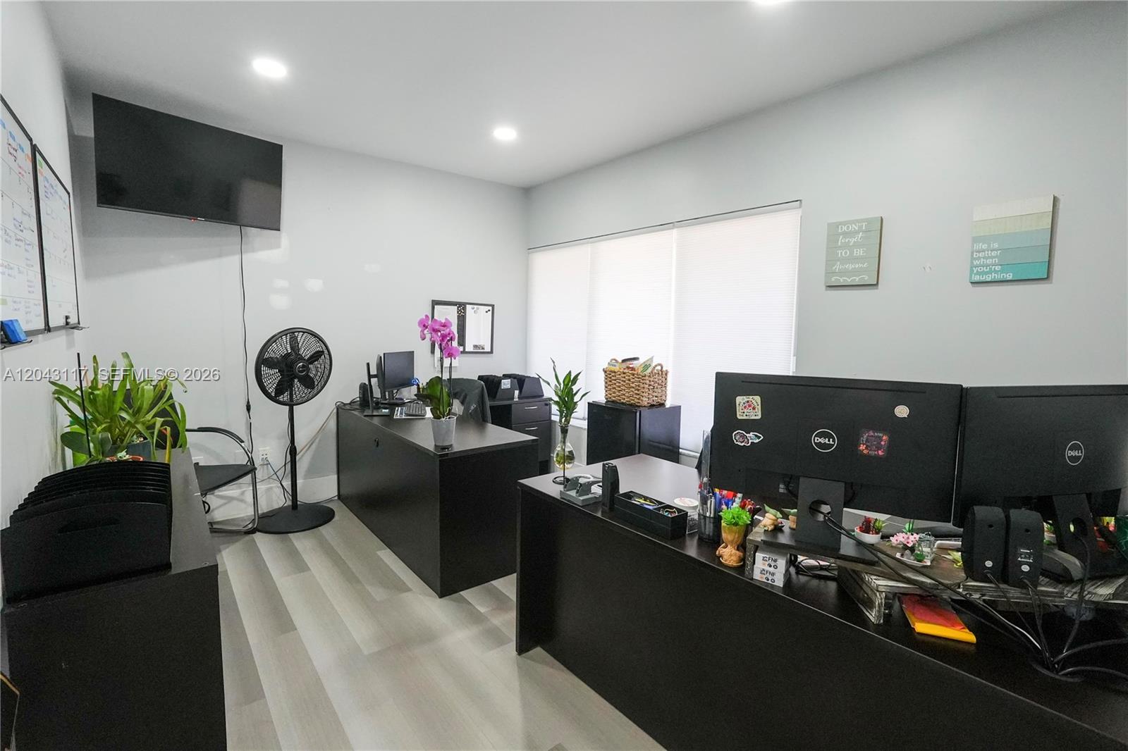 An office space features two black desks, light wood-look flooring, and a wall-mounted television — 8125 SW 120th St, Pinecrest FL 33156, PINECREST, FL
