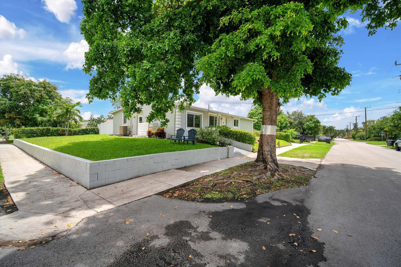 A light-colored house with a large tree and a low concrete wall in the front yard — 7321 Cody Street, Hollywood FL 33024, HOLLYWOOD, FL