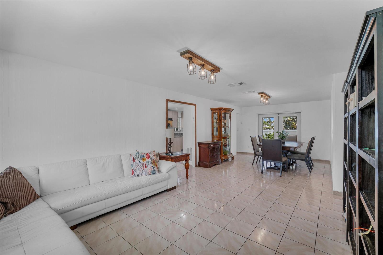 A living and dining area with white walls, tile floors, and two wooden light fixtures — 7321 Cody Street, Hollywood FL 33024, HOLLYWOOD, FL