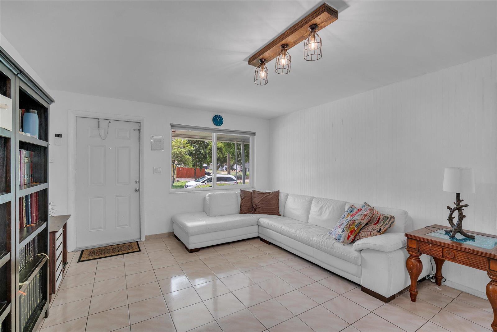 A living room features a white sectional sofa, tile flooring, and a wooden light fixture — 7321 Cody Street, Hollywood FL 33024, HOLLYWOOD, FL