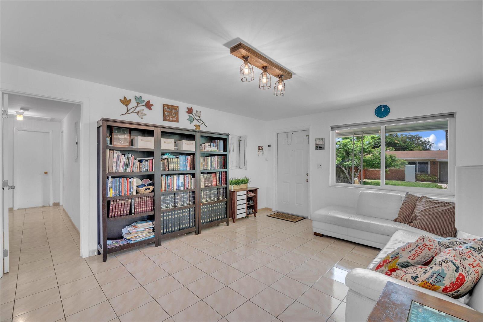 A living room with tile floors, a large dark wood bookcase, and a white sofa — 7321 Cody Street, Hollywood FL 33024, HOLLYWOOD, FL