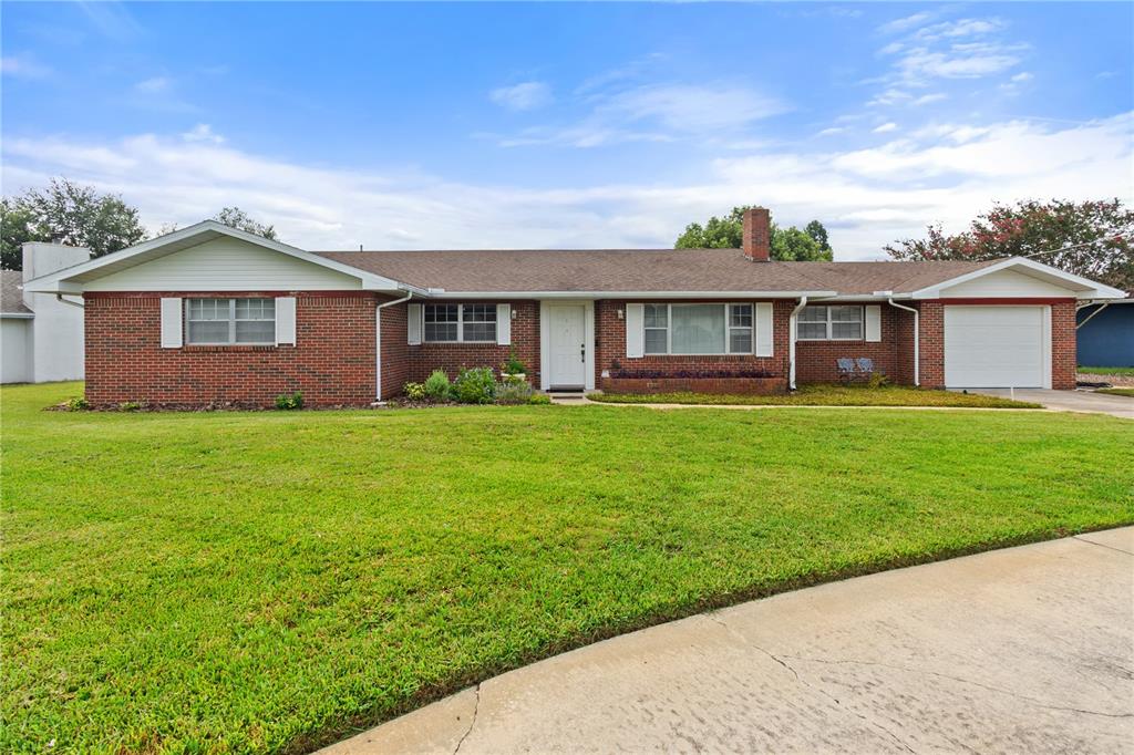 A single-story brick house with a white garage, front door, and a large front lawn — 404 COLEMAN DRIVE, WINTER HAVEN, FL