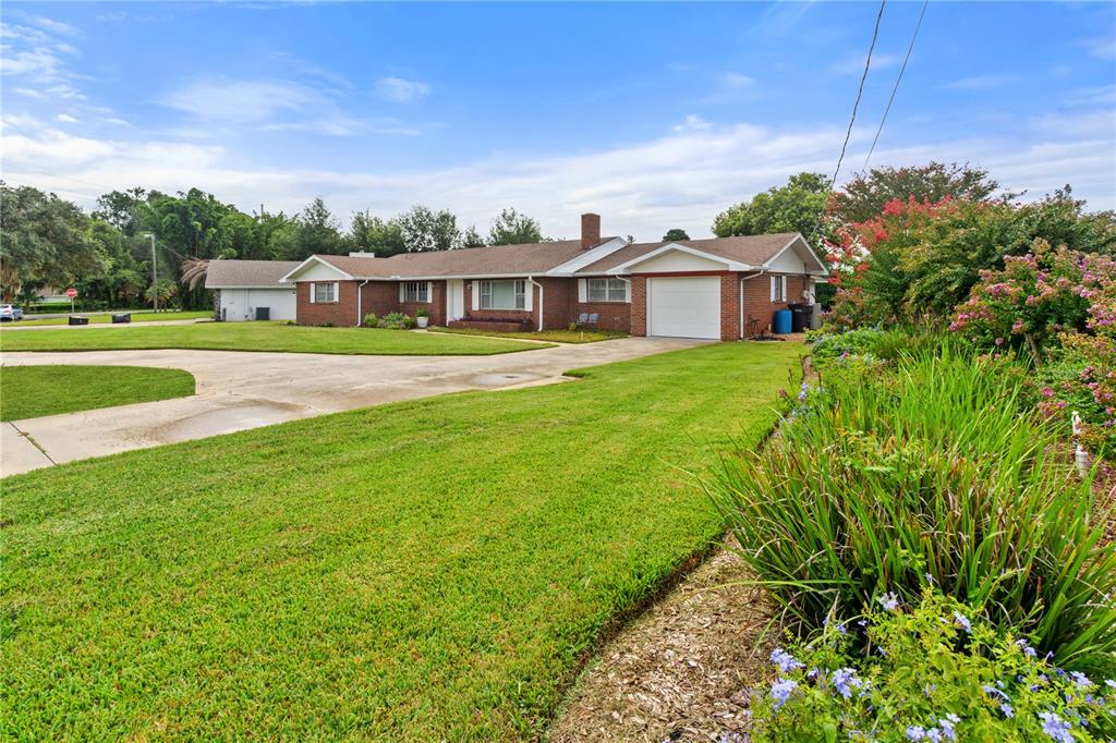 A single-story brick house with a white garage and a large front lawn — 404 COLEMAN DRIVE, WINTER HAVEN, FL